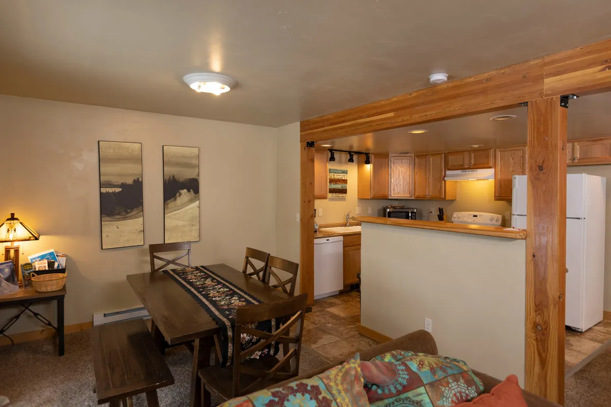 An open-concept dining and kitchen area, with a central dining table surrounded by comfortable chairs, visible kitchen amenities, and decorative artwork. The space is warm and welcoming, ideal for family meals and special occasions.